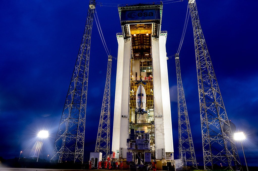 A Vega rocket standing inside its floodlit mobile gantry at Europe's Spaceport in French Guiana at dusk