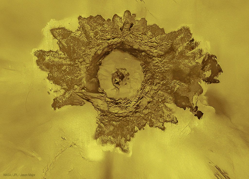 A radar view of the impact crater Adivar on Venus, ringed by bright ejecta streaks across a smooth plain.