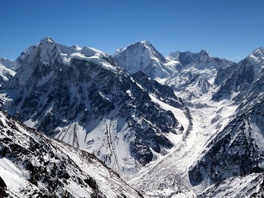 The Langshisa Glacier flowing down a high valley in the Langtang Range of Nepal, between snow-covered ridges