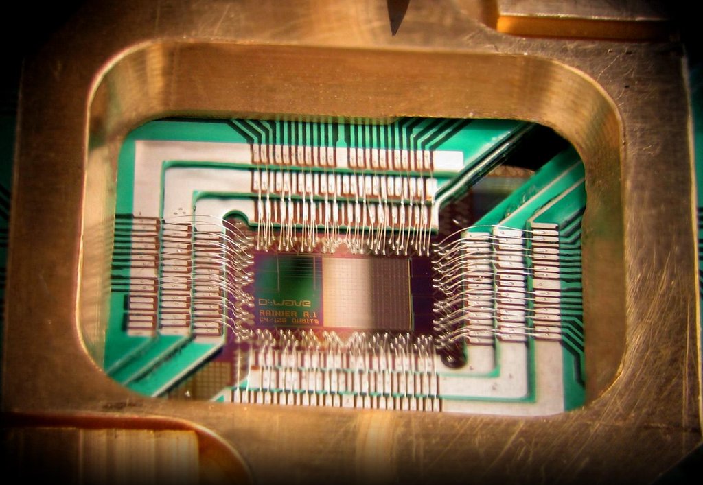 Close-up of a superconducting processor chip wire bonded inside a gold-colored sample holder.