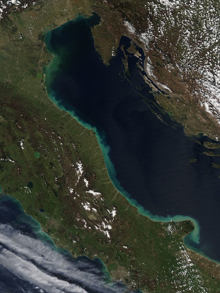 Satellite view of the Adriatic Sea between Italy and Croatia, with pale green sediment plumes from spring river runoff tracing the Italian coast.