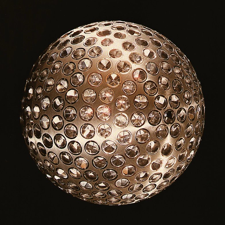 A metal sphere covered in hundreds of small round reflector prisms, photographed against a black background.