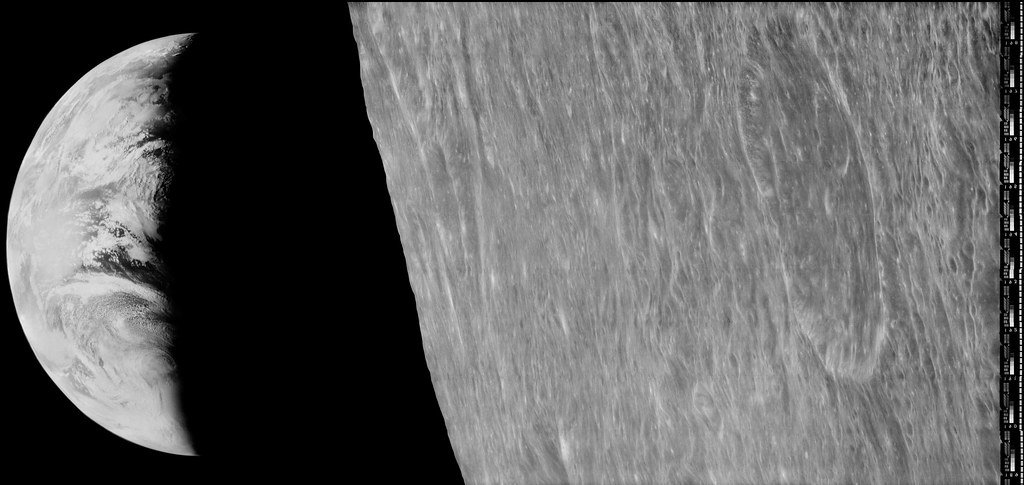 A black and white spacecraft image: a crescent Earth at the left edge beyond the rough, streaked surface of the Moon, with a film data strip along the right edge.