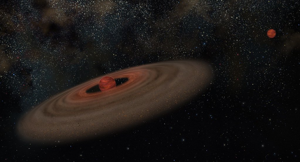 Artist's impression of a brown dwarf, a dim reddish sphere, encircled by a broad disk of dust and rock, with a smaller companion object glowing in the distance.