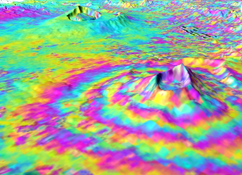 Concentric rainbow-colored fringes draped over a three-dimensional view of a volcano, the pattern produced by comparing two radar passes.