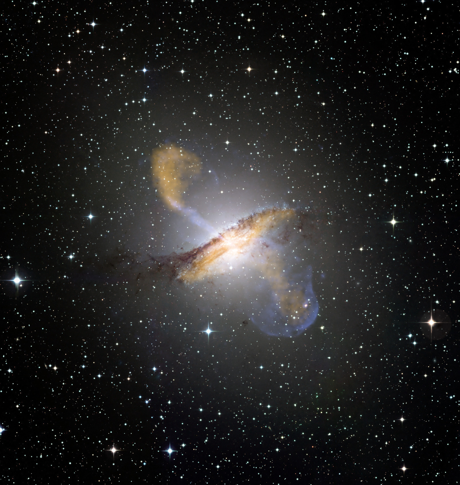 The galaxy Centaurus A: a bright elliptical body crossed by a dark dust lane, with orange and blue lobes of emission reaching out above and below it.