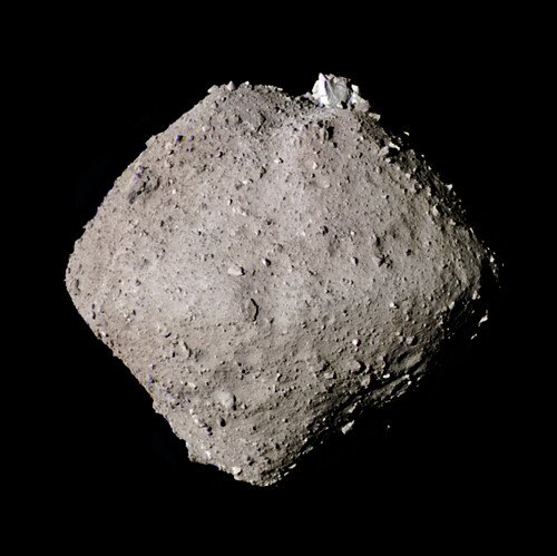 A gray, diamond-shaped asteroid covered in boulders, seen against black space.