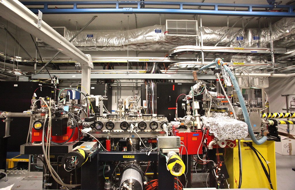 Vacuum chambers, pumps, cabling and foil-wrapped pipework of a soft X-ray beamline in an accelerator experimental hall.