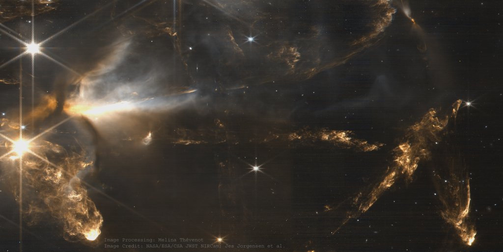 Near-infrared image of bright arcs and knots of shocked gas strung out from a young star across a dark dusty field.