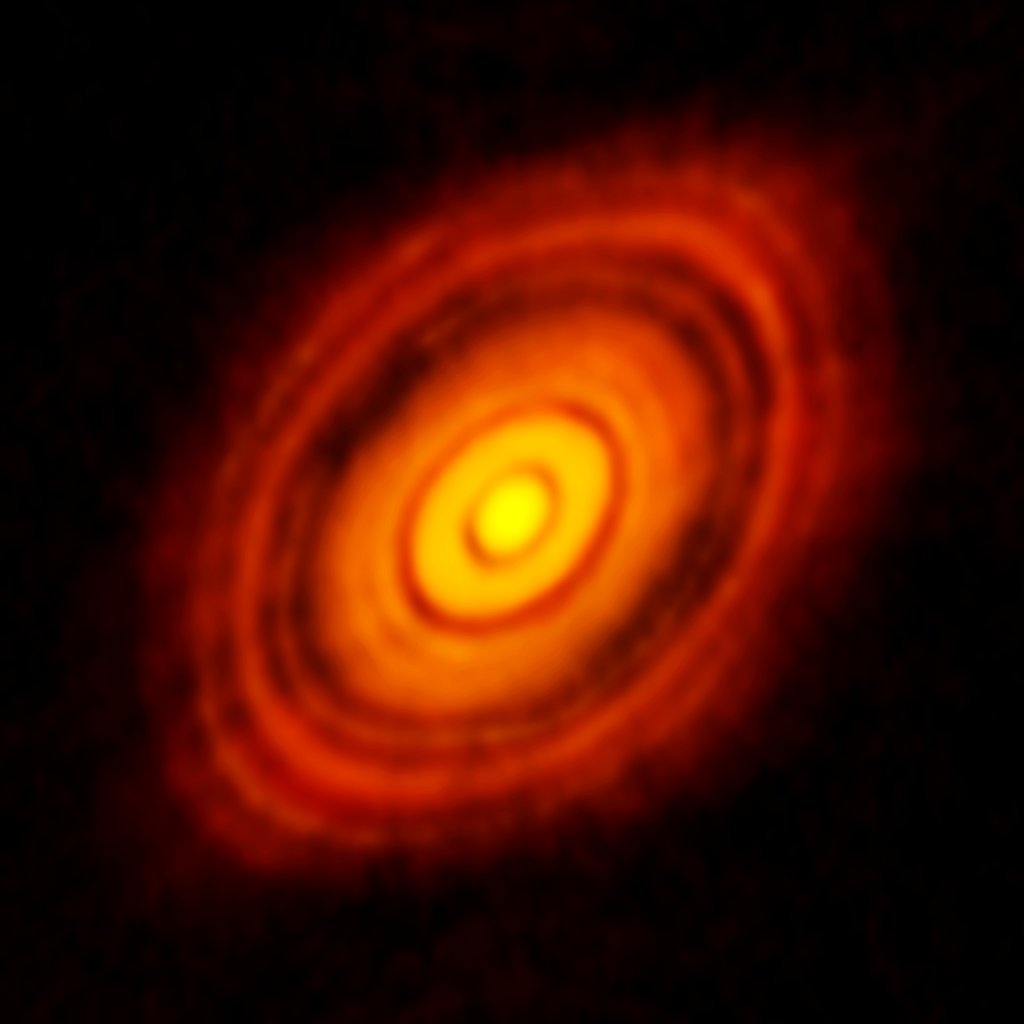 Radio image of a young star circled by a bright orange disk of dust and gas, crossed by dark concentric gaps.