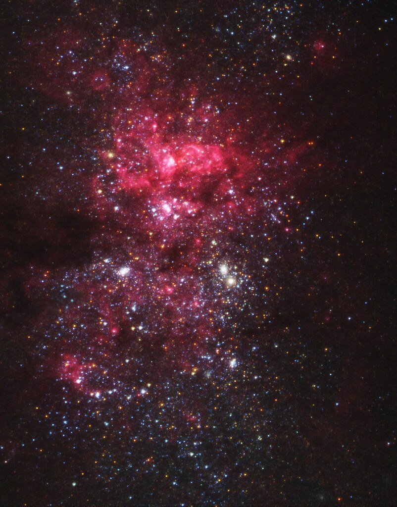 Close-up Hubble photograph of the center of NGC 5253: dense fields of blue and white stars threaded with glowing pink clouds of hydrogen.