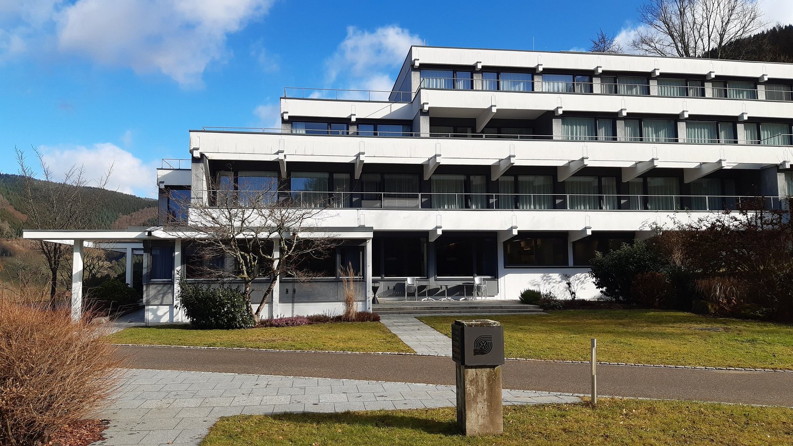 A long white research building with balconies, set among grass and bare trees under a blue sky.