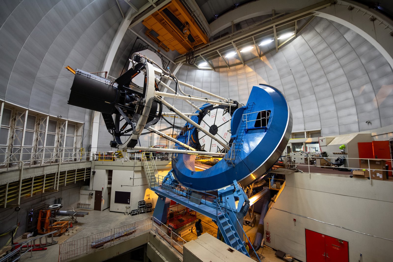 A large telescope with a blue support structure inside a domed observatory building.