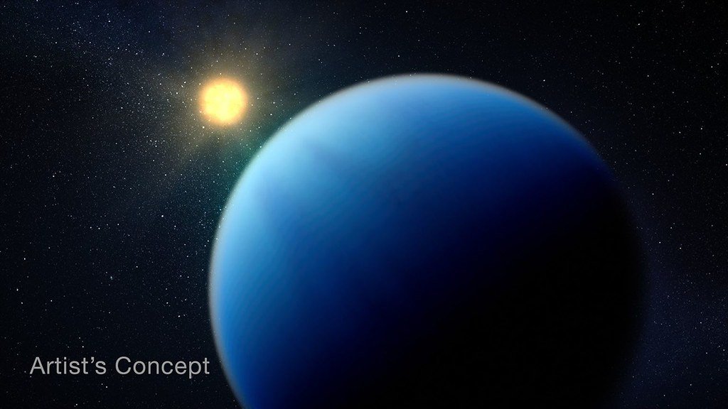 Artist's concept of a blue sub-Neptune planet filling most of the frame, with a small orange star behind it.