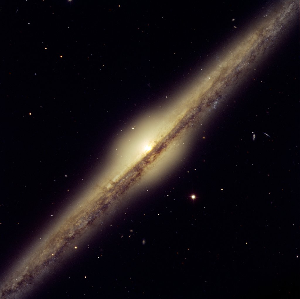 An edge-on spiral galaxy: a thin bright disk crossed by a dark dust lane, with a glowing round bulge at its center.