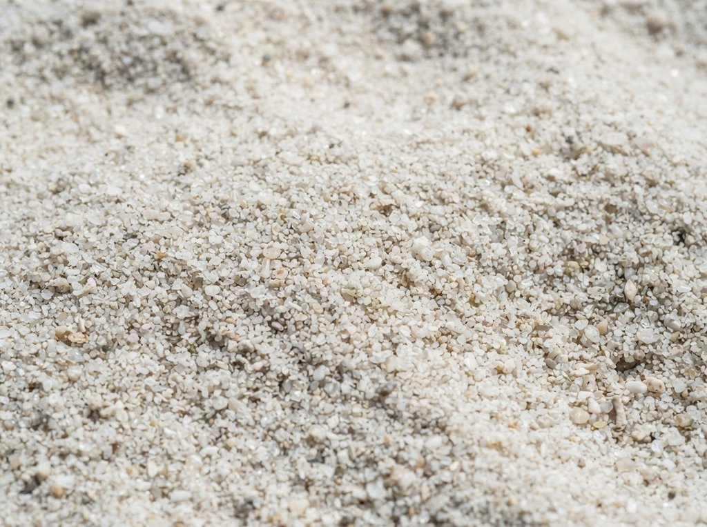 Close-up of pale mineral grains of mixed sizes heaped together.