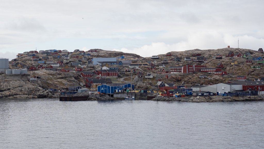 Brightly painted wooden houses on bare gray rock above the waterfront of a small Greenland town.